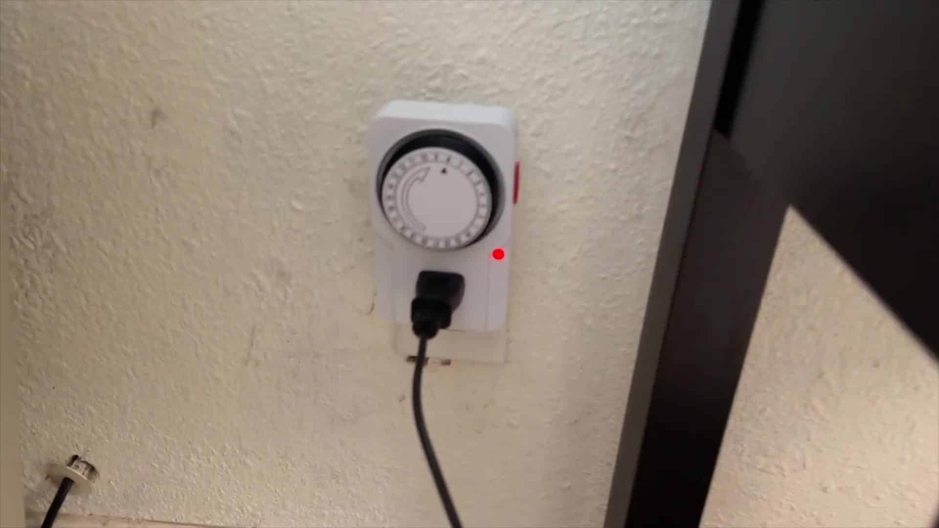 White mechanical outlet timer with 15-minute pins and a red status light